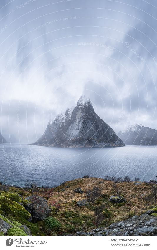 Seaside near rocky mountains against overcast sky sea nature winter fjord picturesque ridge landscape seashore snow seascape reine nordland norway scenery