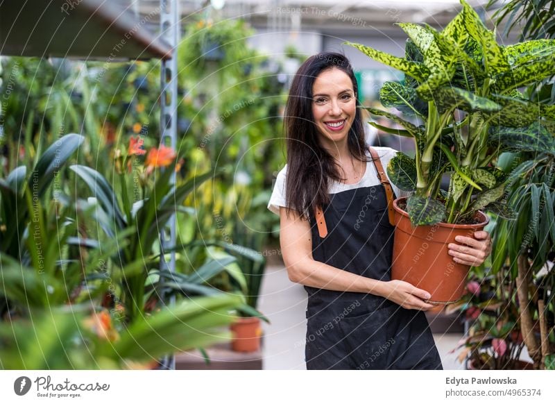 Young woman working in a garden shop plant nursery smiling positivity nature gardening cultivate growth hobby freshness growing flora green flowers planting