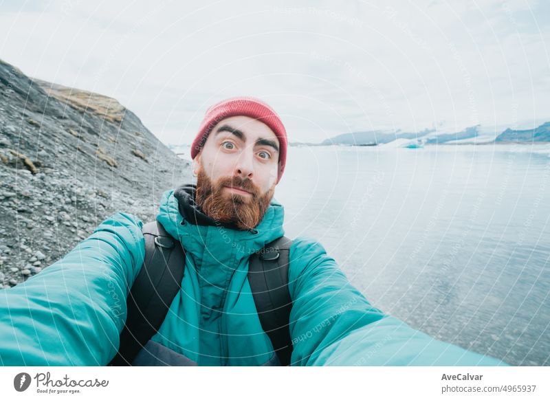 Solo male traveler on Iceland happy bout road trip new experiences. Living freedom and explore backpacking. Bearded hipster handsome guy doing the all good sign to camera taking a selfie while hiking.