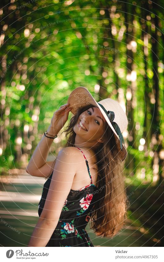 Natural smile with open mouth of a young maiden in a forest setting with a linen hat. Candid portrait of brunette in floral dress elegant glamour passion tender