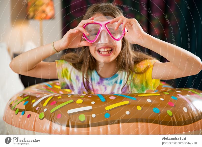 Cute child with inflatable swimming ring and diving mask sitting on bed in hotel room. Playing, laughing, smiling. Happy family vacation. beach bedroom cheerful