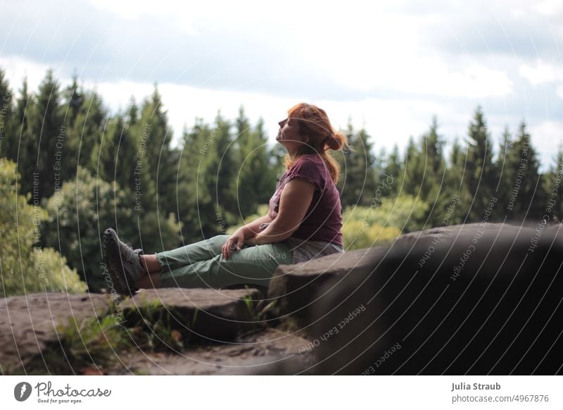 Hiking break on basalt stones Rhön Woman pretty red hair Summer cloudy vacation relaxed rest big stones Black Hiking boots Hiking trip trees Forest clearing