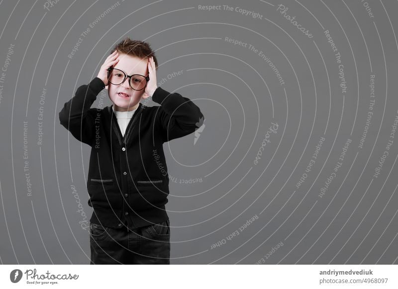 Sad unhappy schoolboy in eyewear having painful look, holding hand on his forehead. Frustrated sick child suffering form terrible headache medical person man