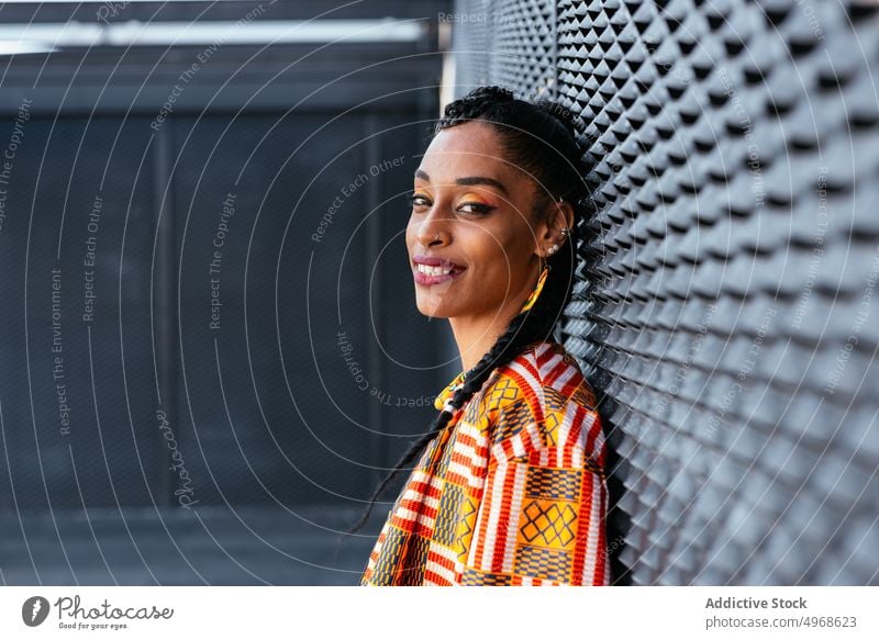 Cheerful ethnic female leaning on wall woman style smile street urban weekend happy portrait young appearance cheerful positive friendly daytime glad optimist