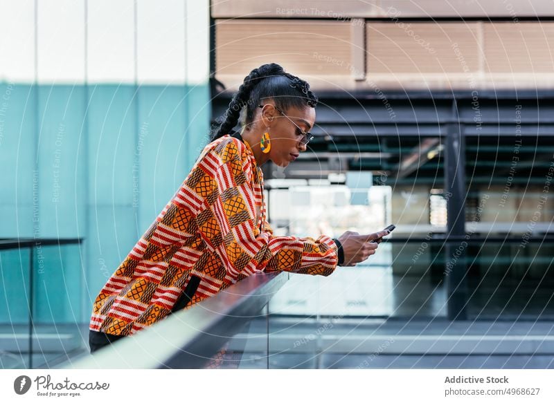 Trendy woman using smartphone on terrace style social media lean fence building modern female young ethnic balcony browsing trendy glass mobile connection