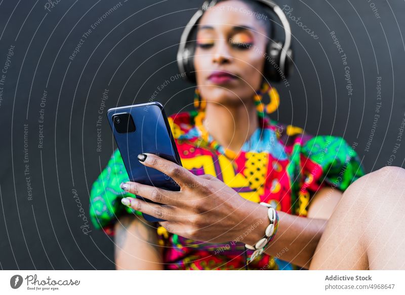 Ethnic woman using smartphone on steps street listen music social media meloman style female young ethnic street style urban colorful gadget device connection