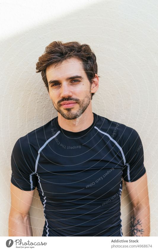 Hispanic sportsman leaning on wall street fitness training break urban portrait activewear male hispanic ethnic adult healthy lifestyle vitality sportswear