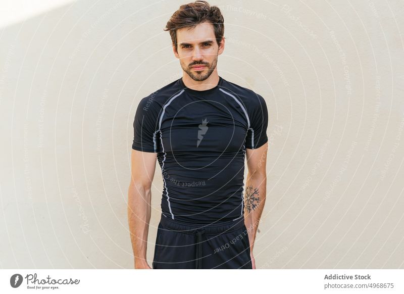 Hispanic sportsman leaning on wall street fitness training break urban portrait activewear male hispanic ethnic hand in pocket adult healthy lifestyle vitality