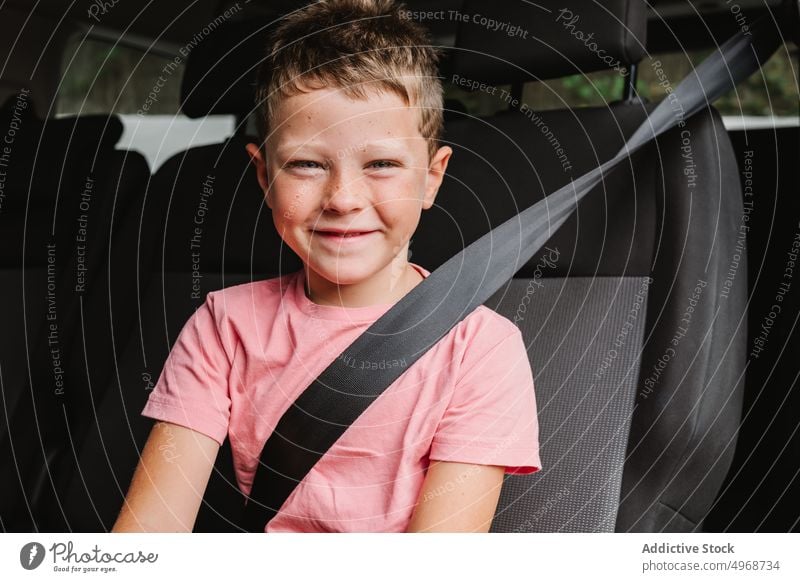 Cheerful boy sitting in car smile backseat road trip happy weekend travel passenger casual kid journey positive transport auto vehicle ride child cheerful