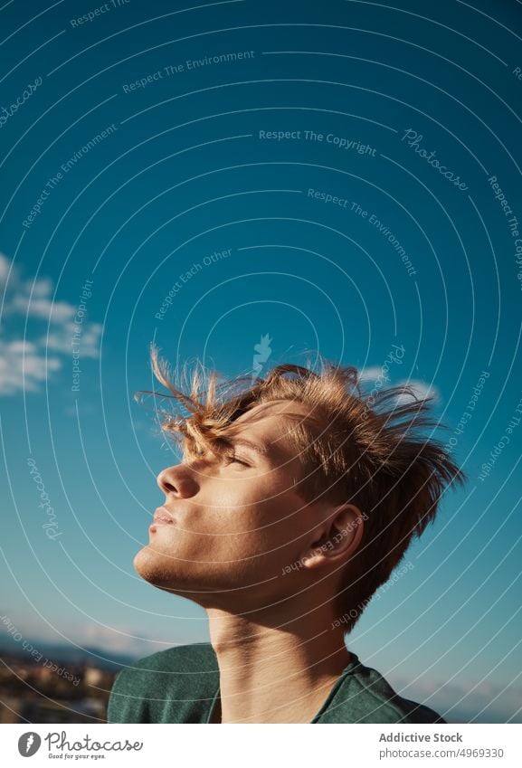 Young blond man looking up the sky relaxed enjoyment urban trendy comfortable stylish young male handsome cute attractive serious mature fashionable elegant