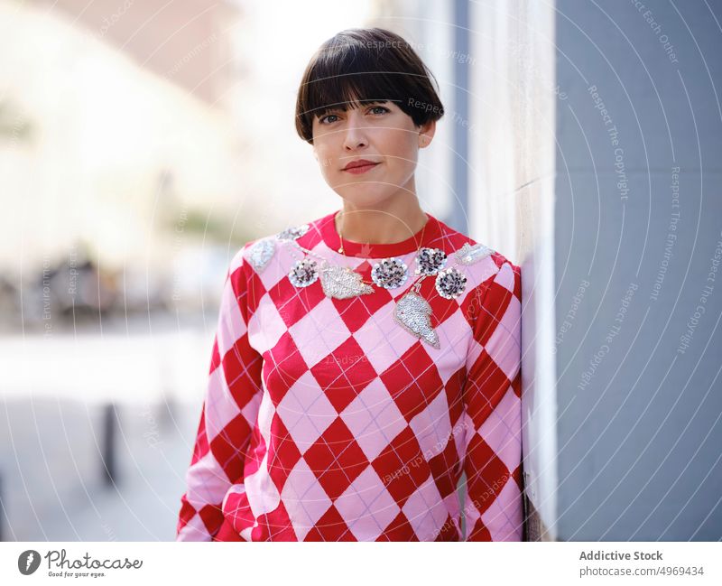 Stylish woman in retro clothes on street vintage style fashion plant serious charismatic female leaning hedge green stand summer trendy positive lady short hair