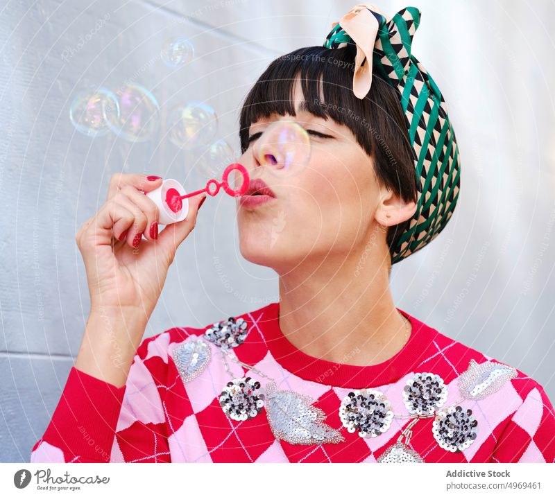 Childish woman blowing bubbles on street vintage playful bandana soap bubble having fun female city fashion classy summer joy relax smile cheerful content