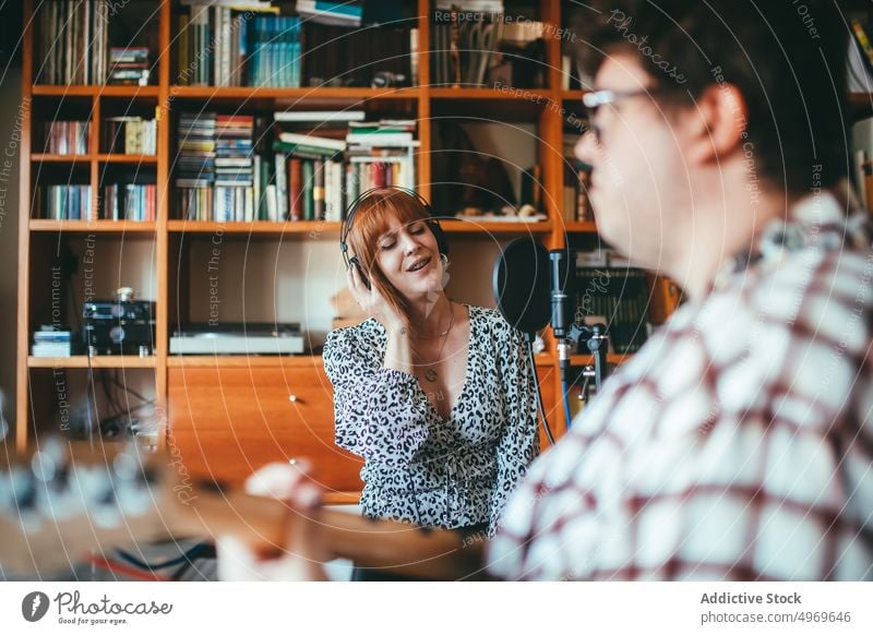 Musician playing guitar against singer at home musician rehearsal melody smile woman show guitarist instrument musical point up attention indicate mic