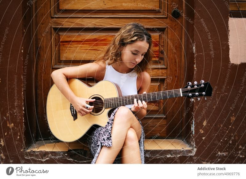 Woman playing guitar in the street woman sitting building music road architecture instrument female musical geometric urban vacation fashion house holiday