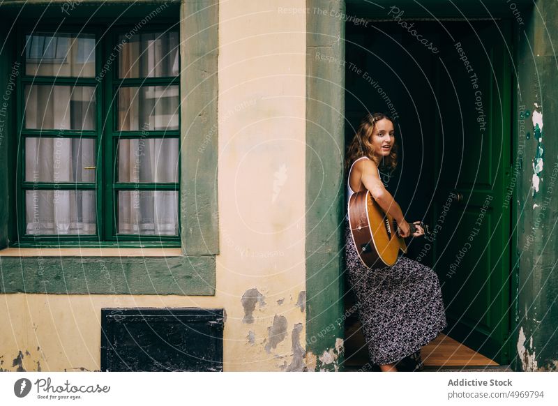 Curly woman playing guitar leaning on the wall music romantic young instrument cheerful female musical fun vacation fashion holiday casual summer creative