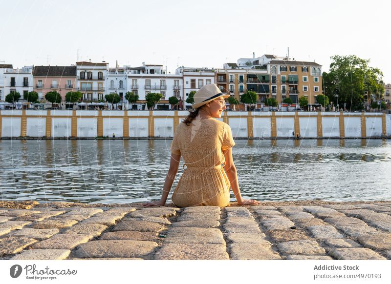 Woman in dress sitting on city embankment at sunset woman summer evening river promenade stroll female waterfront stone town shore twilight urban sundown