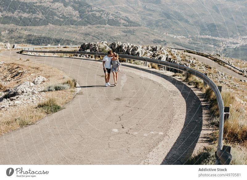 Content couple on lonely winding road walk route love together casual male female nature smile holding hands relax lifestyle young harmony serene tender