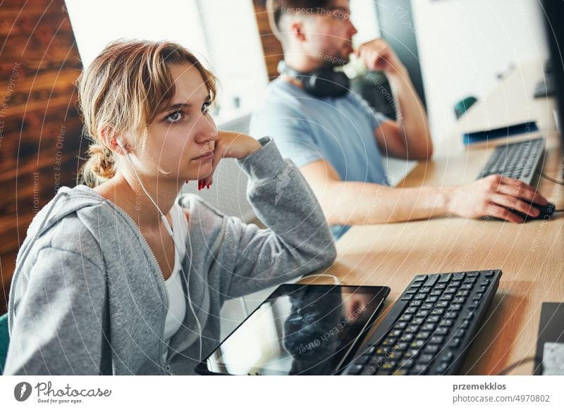 Students learning in computer classroom. Young man preparing for test on computer. Girl writing essay and making notes using computer. Focused students studying for college exams