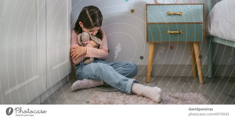 Sad girl hugging stuffed toy sitting on the floor little sad depressed mental disorder bedroom fear sadness banner web header panorama panoramic problem teddy