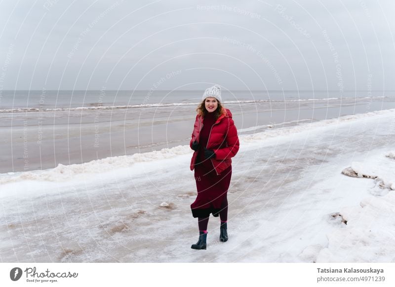 Winter walk along the sea, a woman walks and smiles female chill whether Emotion joy cheerful red jacket vacation Journey adventure activity Woolly hat Smiling