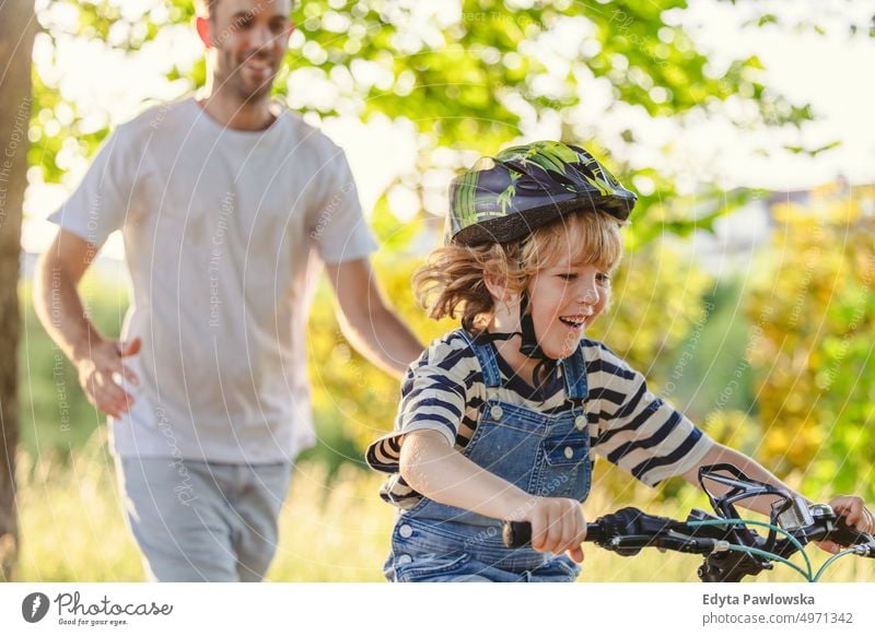 Father teaching his son how to ride a bicycle day healthy lifestyle active lifestyle outdoors fun joy cycling biking activity bike cyclist enjoying ecological