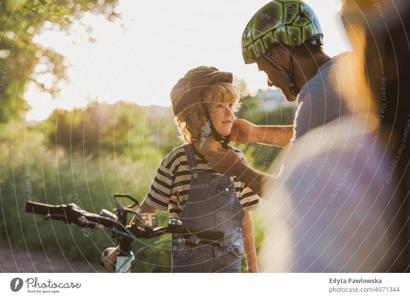 Shot of a father adjusting his son's helmet day healthy lifestyle active lifestyle outdoors fun joy bicycle cycling biking activity bike cyclist enjoying