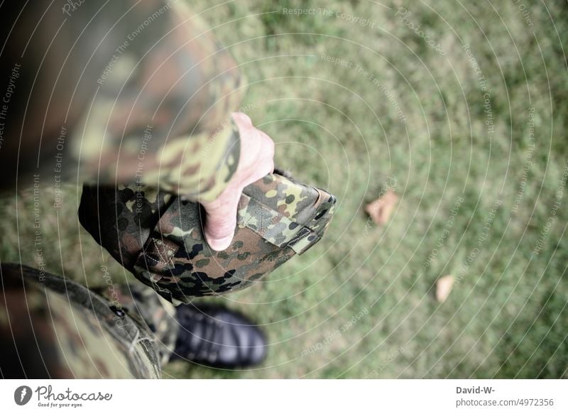 Soldier with battle helmet in hand Federal armed forces War Peace Man Uniform Army military Germany compulsory military service Protection Camouflage Field suit