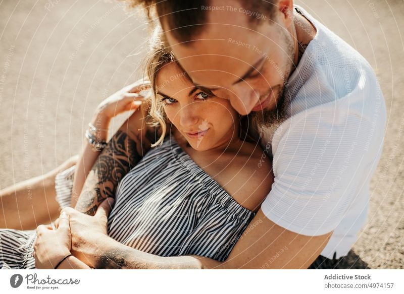 Young couple enjoying each other while sitting on road and embracing love hug hipster romantic sensual relationship happy street admire fondness girlfriend