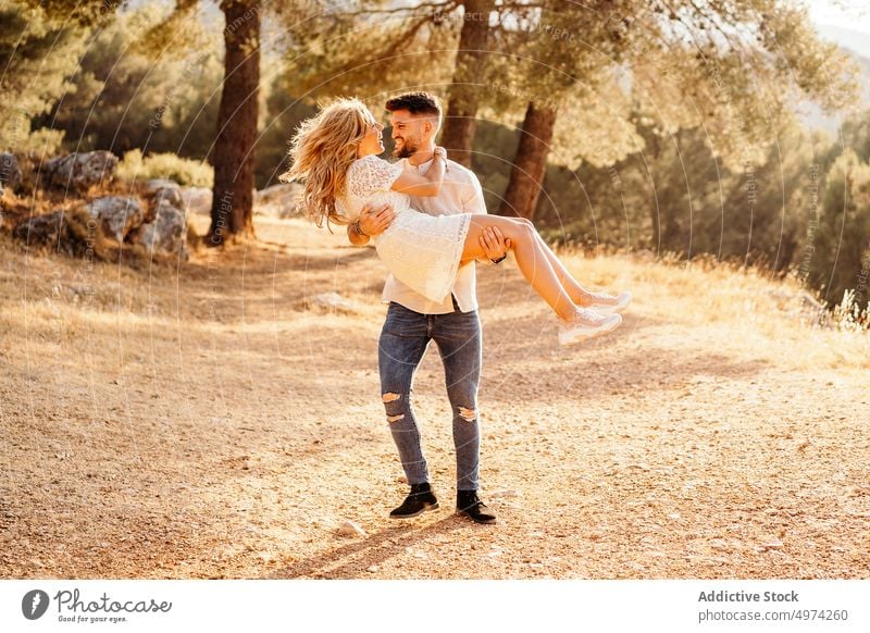 Happy man carrying on hands cheerful girlfriend while having date in park couple happy excited love tender hug care embrace bonding honeymoon forest boyfriend