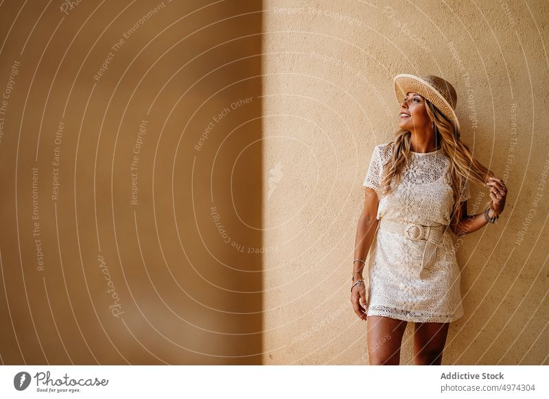 Stylish happy woman smiling away and thinking in lobby of modern building confident dress hat dream smile trendy charming blond fashion fit female lace joy