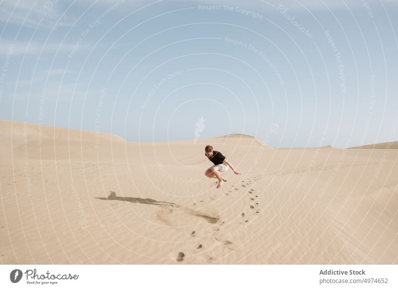 Man jumping on sand land and blue sky spain dune hand side desert sunset freedom heaven evening young summer nature picturesque europe landscape travel female