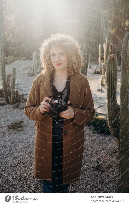 Portrait of beautiful curly blonde woman using a retro camera portrait model outdoors winter fashion face accessory apparel clothing coat confident cute elegant