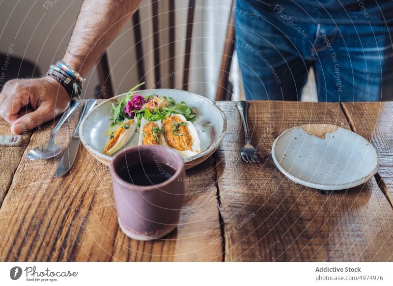 Faceless man having breakfast in morning time dish food table meal style casual served ceramic bruschetta coffee beverage lean male bright wooden bracelet