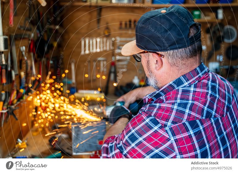 Male cutting piece of metal in modern workshop man angle grinder spark worker equipment using workplace instrument mechanic craftsman process industry garage