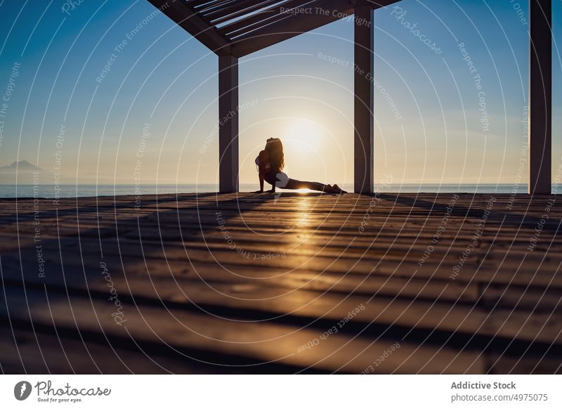 Flexible woman doing yoga on beach pose asana sunrise seaside stretch practice concentrate harmony healthy balance relax calm position peaceful morning body