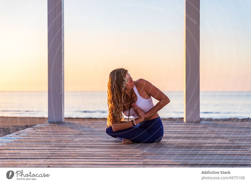 Flexible woman doing yoga on beach pose asana sunrise seaside stretch practice concentrate harmony healthy balance relax calm position peaceful morning body