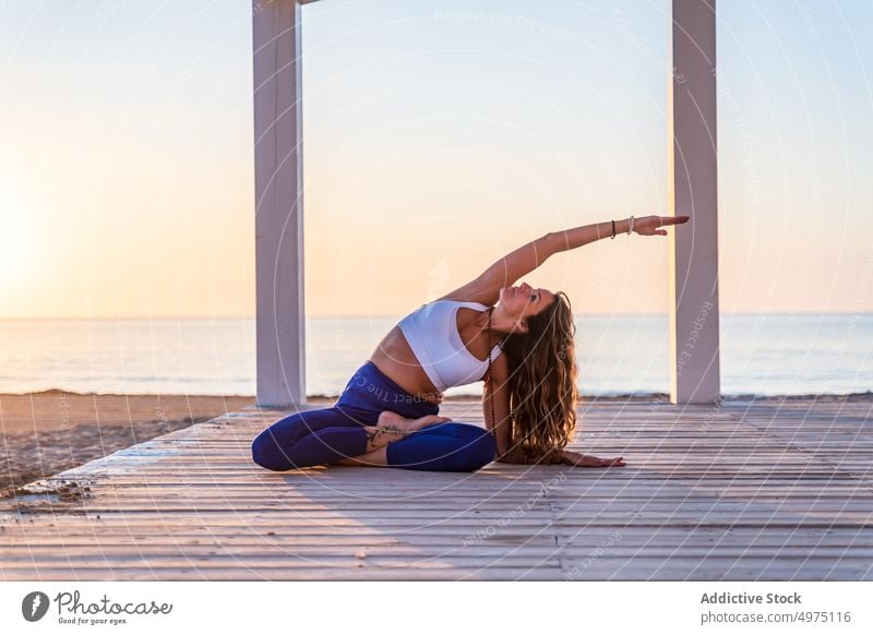 Flexible woman doing yoga on beach pose asana sunrise seaside stretch practice concentrate harmony healthy balance relax calm position peaceful morning body