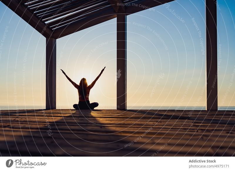 Calm woman in lotus pose at seaside during sunrise yoga silhouette meditate morning harmony asana female terrace wooden padmasana slim dawn healthy relax