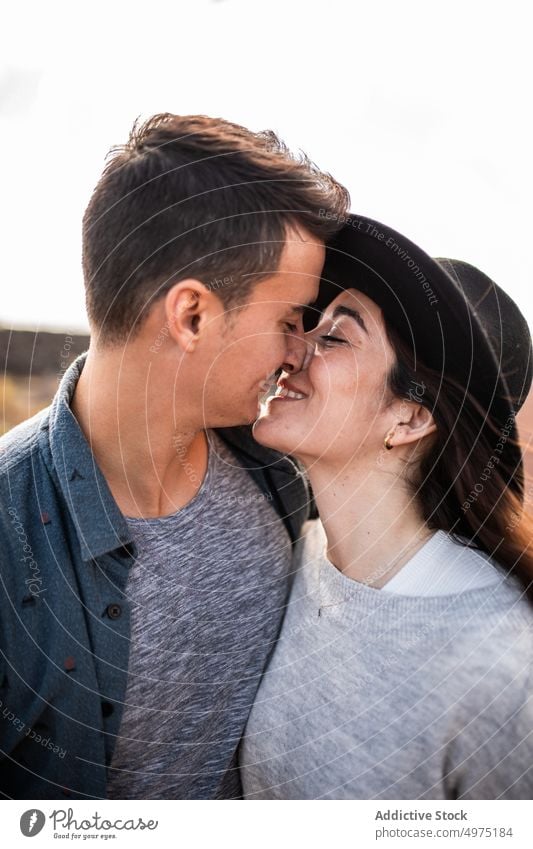 Smiling young ethnic couple hugging on rural road on sunny day cuddle smile trip romantic together love affection fondness style volcanic terrain boyfriend