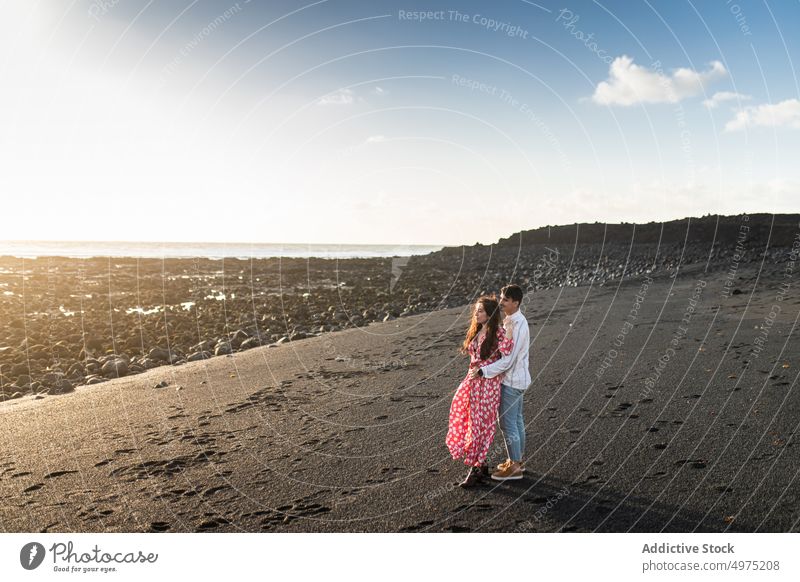 Romantic young ethnic couple cuddling on sandy seashore on sunny day embrace romantic love beach happy affection gentle together summer holiday boyfriend