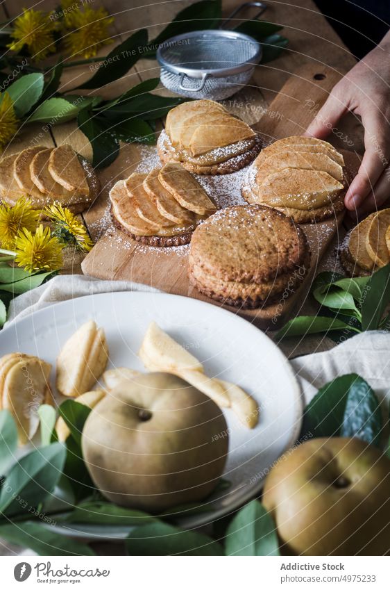 Crop person taking tartlet from table apple dessert kitchen home food fresh delicious meal tasty cookie yummy sieve biscuit gourmet nutrition tool icing