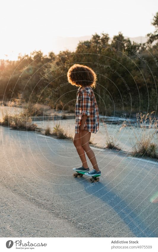 Ethnic woman riding penny board ride sunset road summer hipster skater afro urban female ethnic street trendy tranquil entertain city chill evening sundown