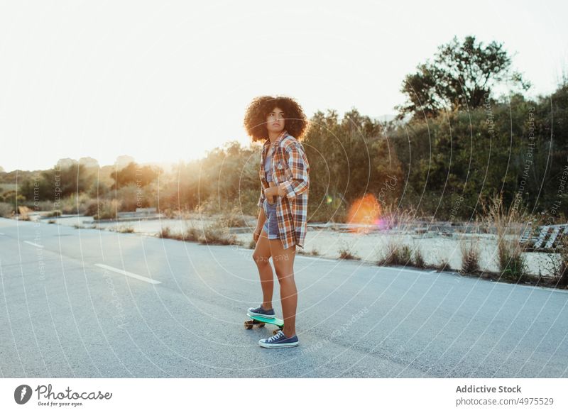 Ethnic woman riding penny board ride sunset road summer hipster skater afro urban female ethnic street trendy tranquil entertain city chill evening sundown