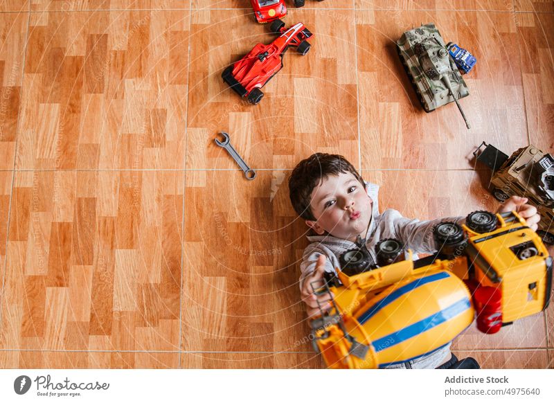 Happy boy playing with toy cars kid vehicle happy cheerful portrait floor game little lying child male childhood playful entertain home smile laugh excited joy