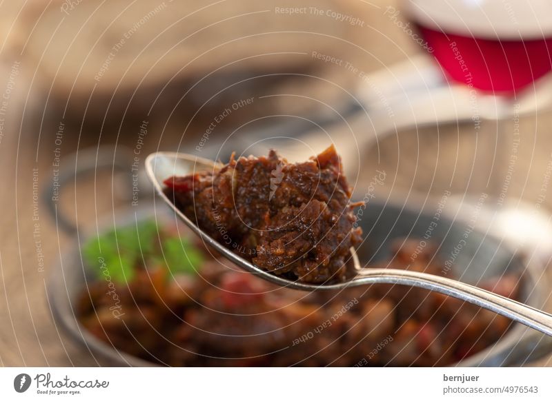 Portion of Austrian goulash on wood Goulash Meat bite Spoon Pot Baked dish Bourguignon Boeuf potato no people Potatoes dressed Plate plan Bread Frying pan