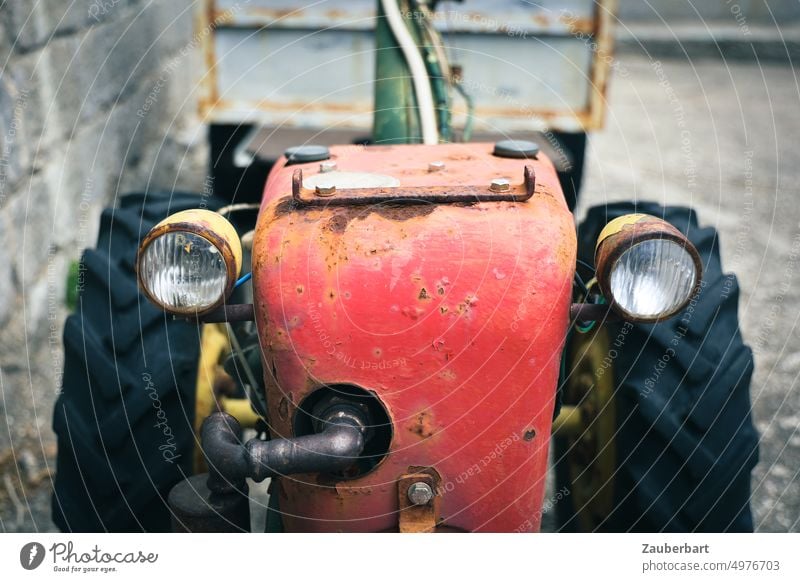 Old red tractor with two headlights, rust stains and friendly "face" Tractor Red rusty Floodlight Exhaust Tire kind work Garden Agriculture Machinery Vehicle