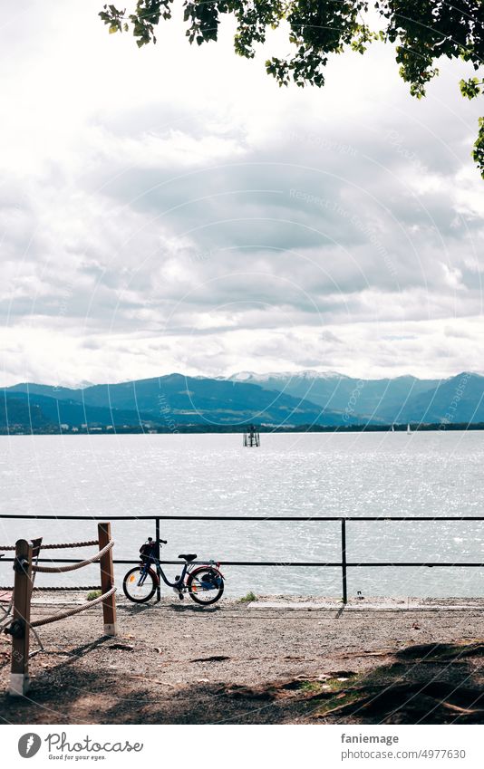 kleines Fahrrad Kinderfahrrad Bodensee See Geländer Fahrradtour Wolkig Wolken bewölkt Süddeutschland Baum Berge Panorama Landschaft blau grün Kies Hafen Lindau