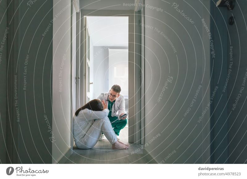 Doctor trying to help patient with mental disorder who refuses help doctor female woman refusing hand sitting floor hospital mental health center copy space