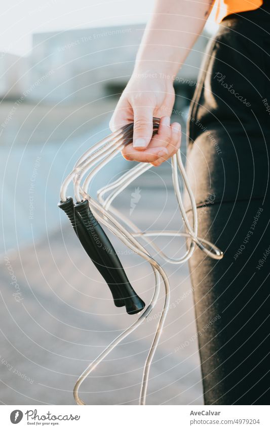 Close up of young hand holding a jump rope training outside. Preparing herself for coaching. Cardio exercises, intense and daily routine. Tone and stretch the body with rest blocks. Banner workout