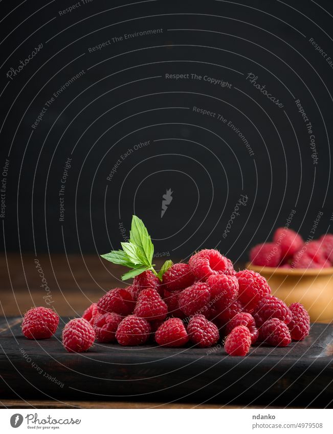 Ripe red raspberries on a brown wooden board raspberry raw ripe seed sweet tasty vegetarian vitamin whole leaf eat food fresh freshness fruit group heap